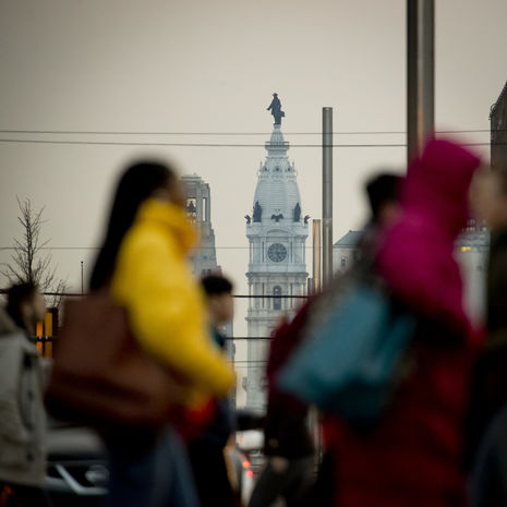 Students walking across Broad Street with Philadelphia's City Hall in the skyline