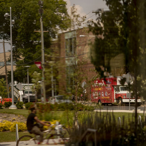 Temple campus stock photo with bicyclist riding through trees and food trucks on the street