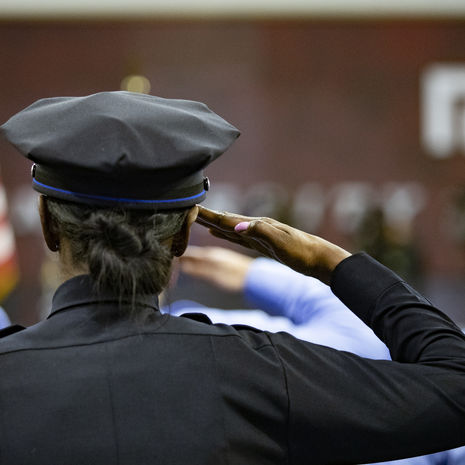 Temple Police Officer saluting the flag during graduation.