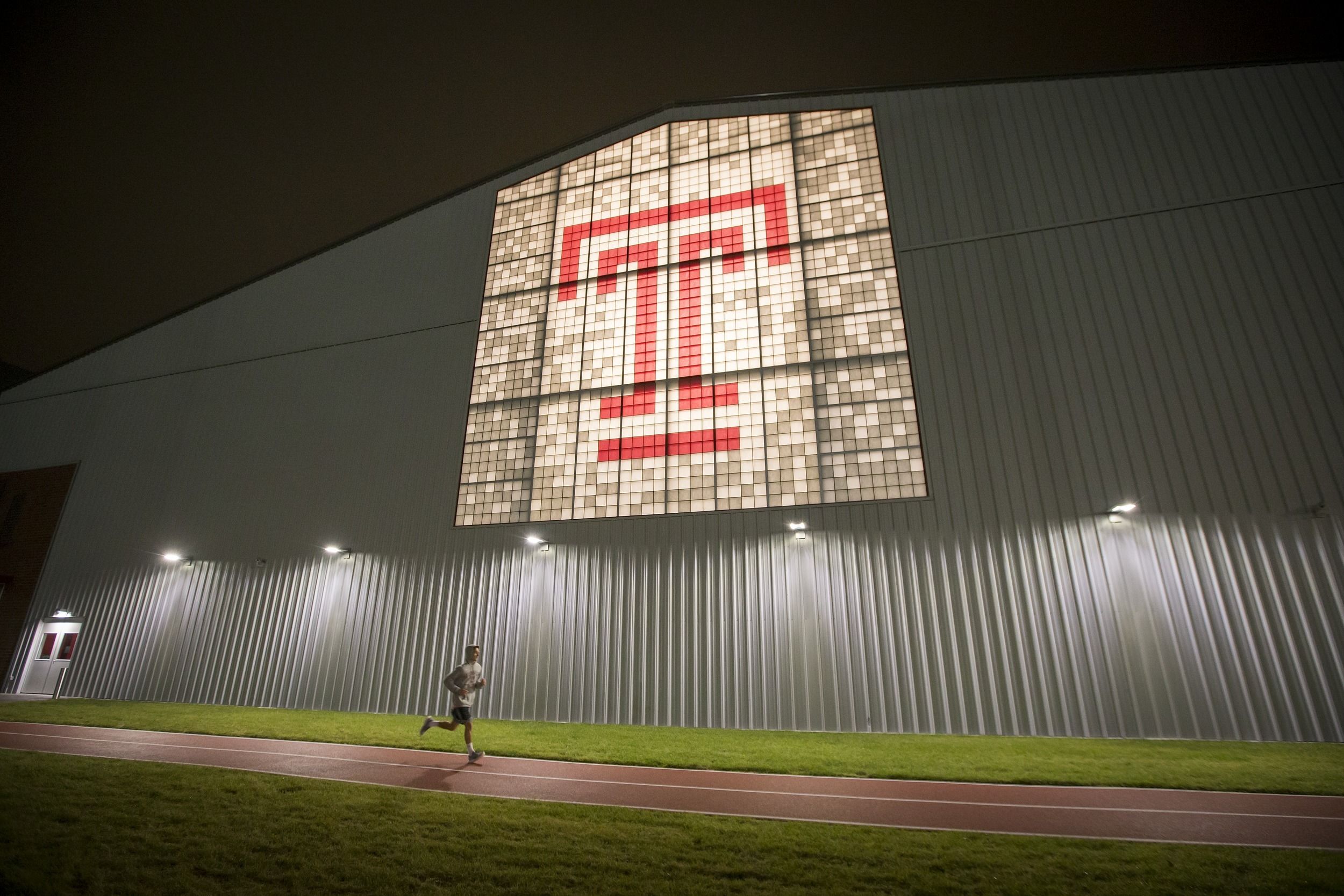 student running around the STAR Complex outdoor track at night.