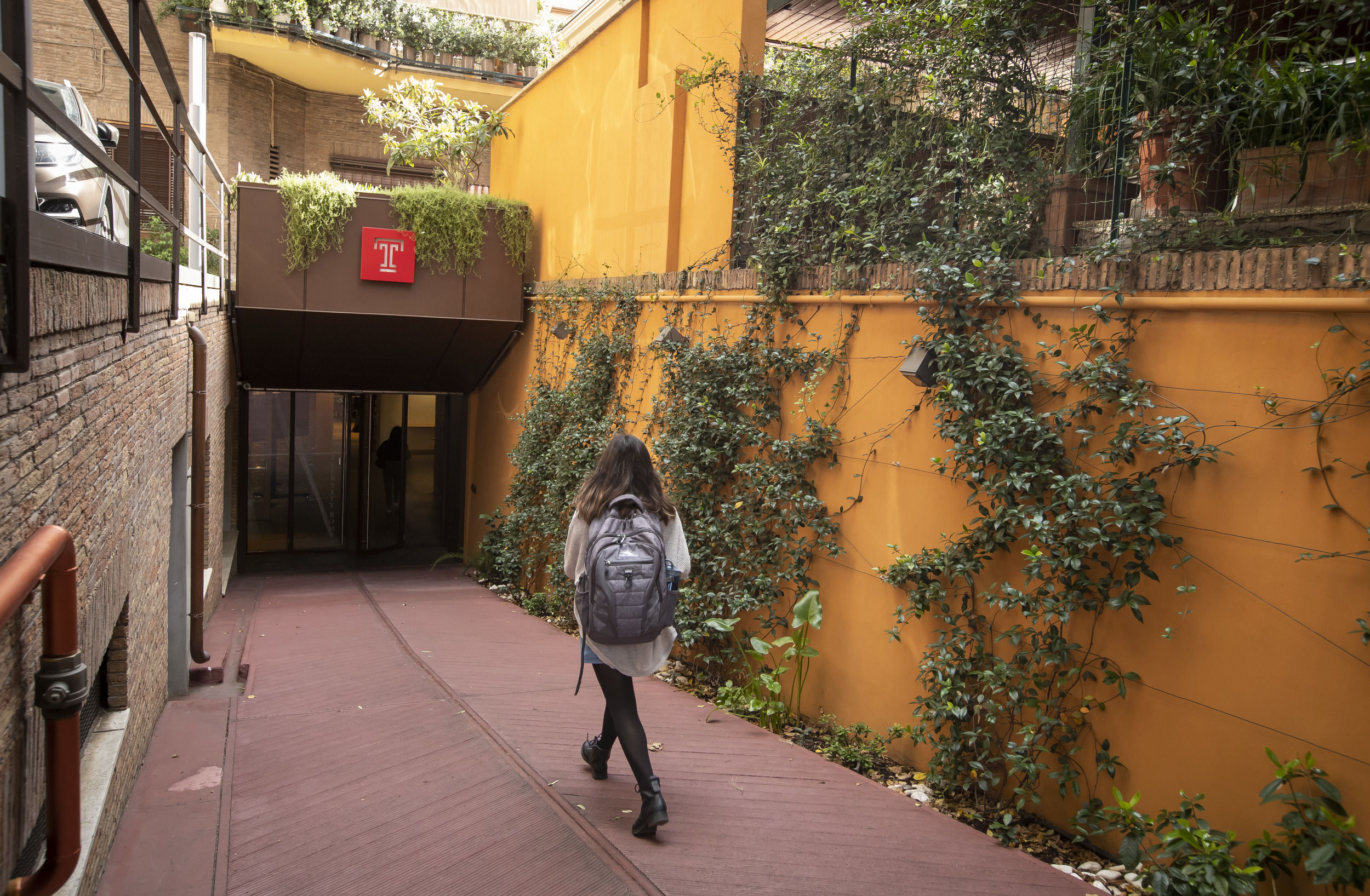 A student walking towards the entrance of a building on the Temple Rome campus.