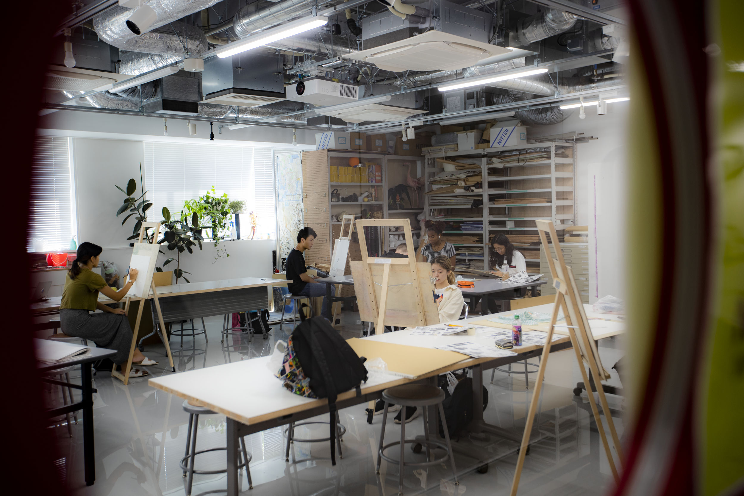 Art students sketching on canvases in class.