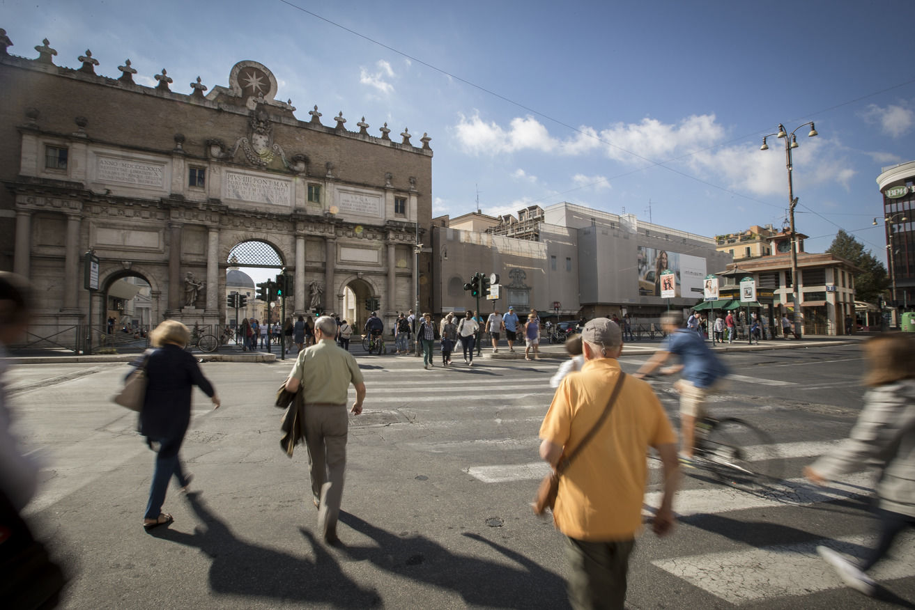 Pedestrians crossing a busy intersection in central Rome.