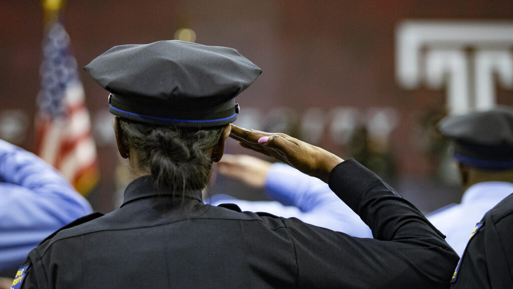 Temple Police Officer saluting the flag during graduation.