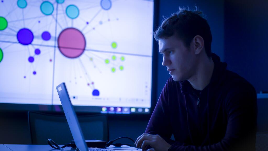 A student sits at a laptop computer.
