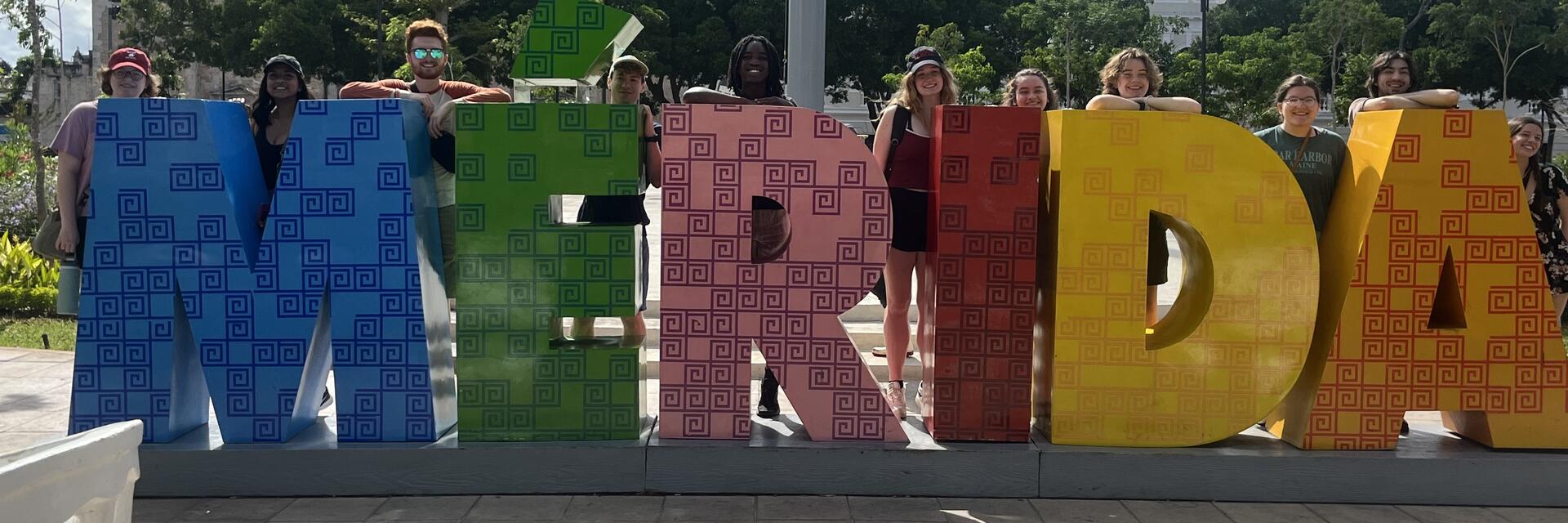 Students posing behind the MERIDA sign in Mexico