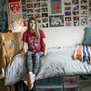 student sitting on her bed in her dorm room.