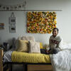 A smiling Temple student sits on their bed in their dorm room.