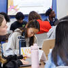 three students sitting at a table doing coursework