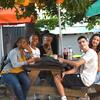 A group of pre-college students and mentors sit at a wooden picnic table at Spruce Street Harbor Park.