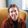 headshot of Lizzie Yazvac, smiling on a yellow chair