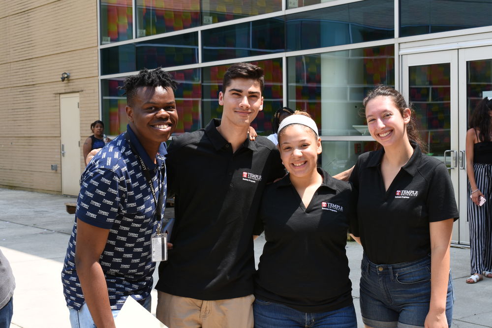Four of Temple's pre-college mentors stand together with arms around each other smiling for a photo.